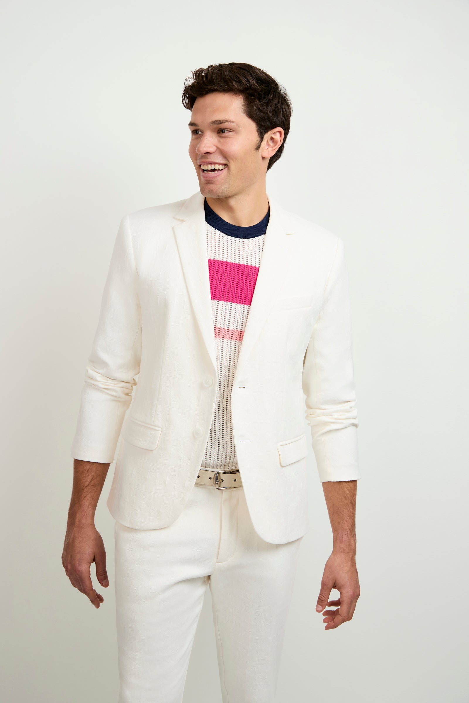 A man wearing the Thurston Blazer - Tegola Textured Jacquard stands against a plain white background, smiling and looking to the side.
