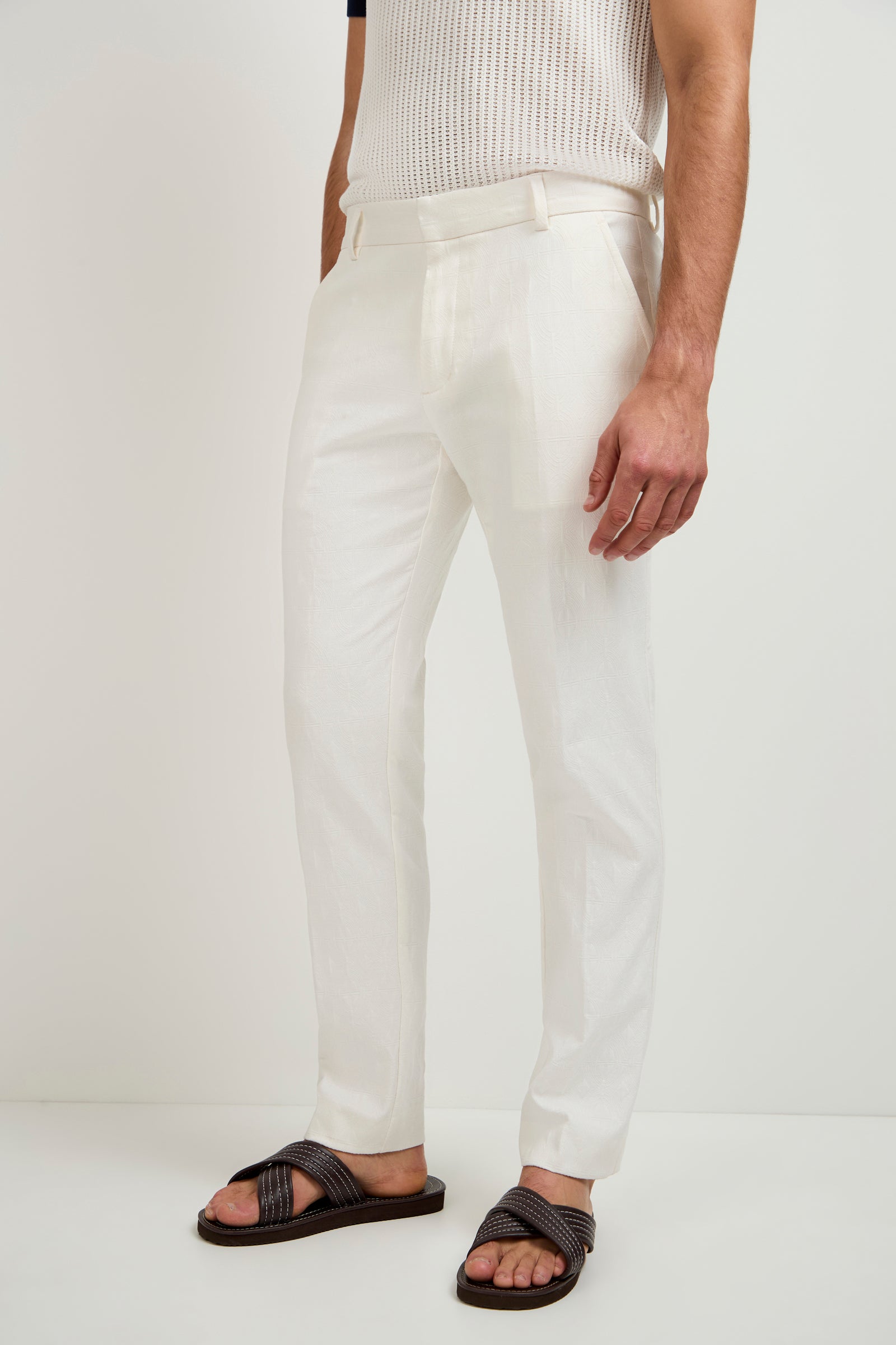 A person stands against a white background wearing the Clyde Slim Trouser in Tegola Textured Jacquard. Only their lower body is visible.