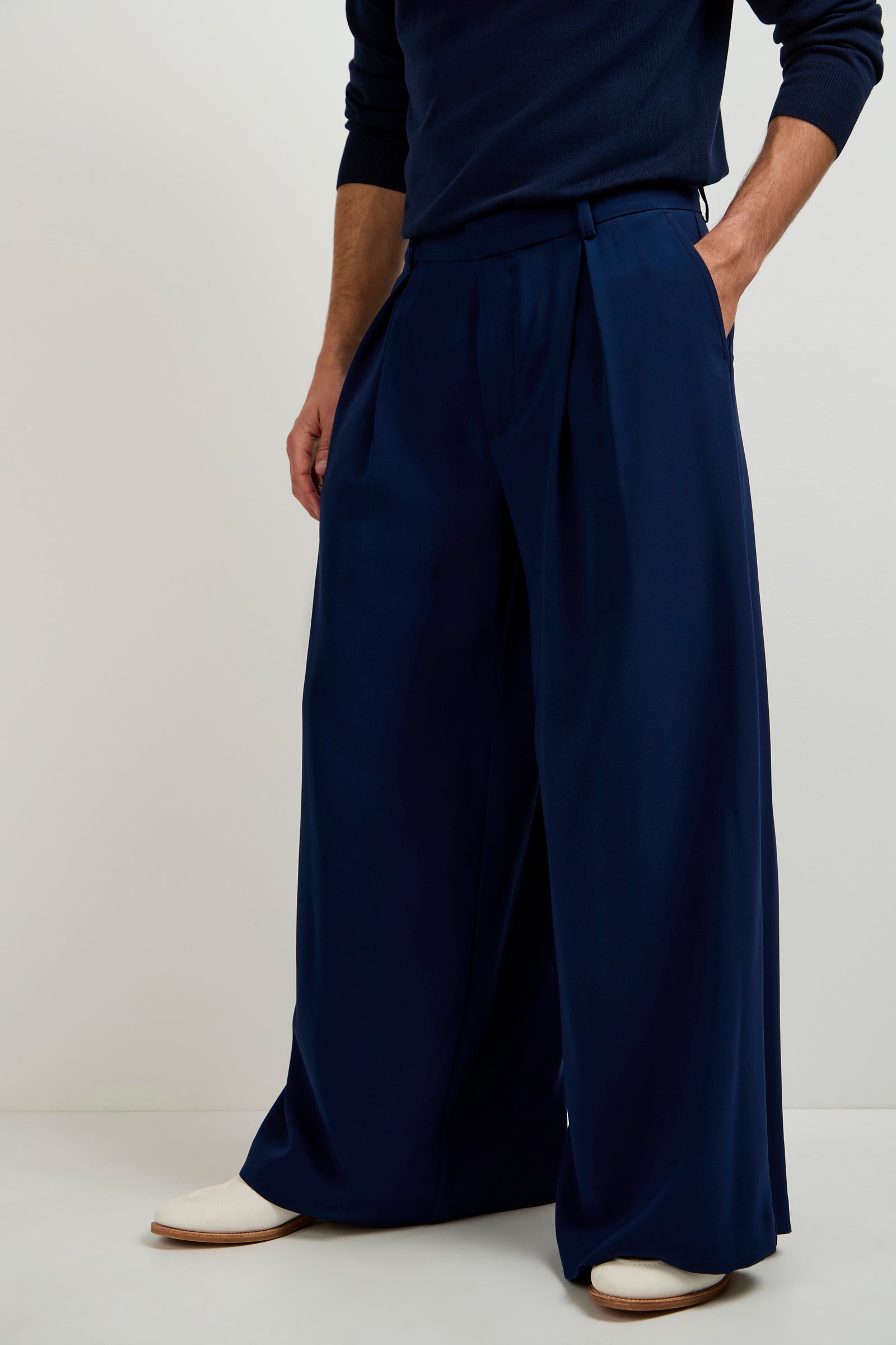 A person wearing Clyde Wide-Leg Trousers in navy with a matching top and white shoes stands against a plain light background, one hand in their pocket.