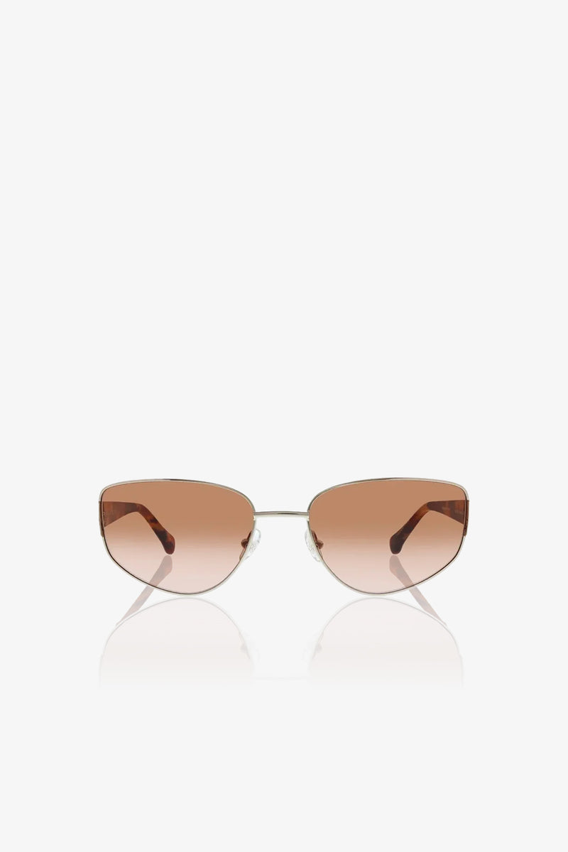 The Dunes Sunglasses feature brown-tinted, cat-eye shaped lenses and thin metal frames, shown against a white background.