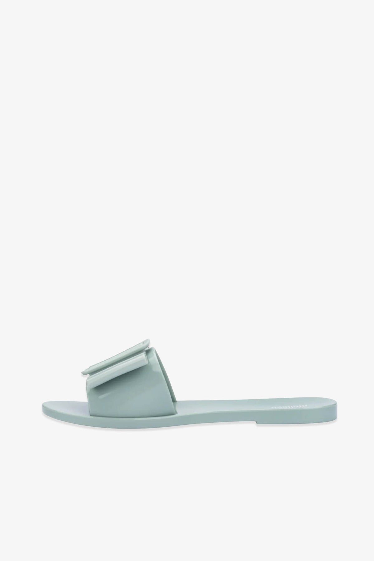 The Babe Sandals are flat slide sandals in light blue, featuring a wide strap adorned with a large decorative bow, displayed against a plain white background.