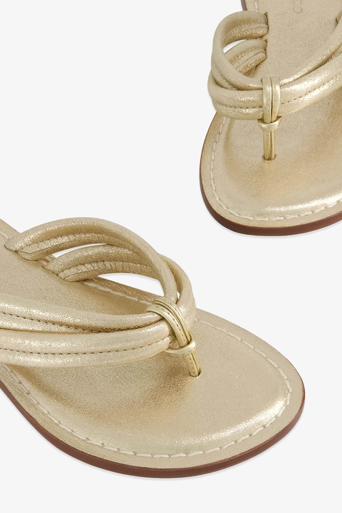 Close-up of the Miami Sandal, featuring gold metallic thong styling with looped straps and a small gold ring detail on the upper, shown against a white background.
