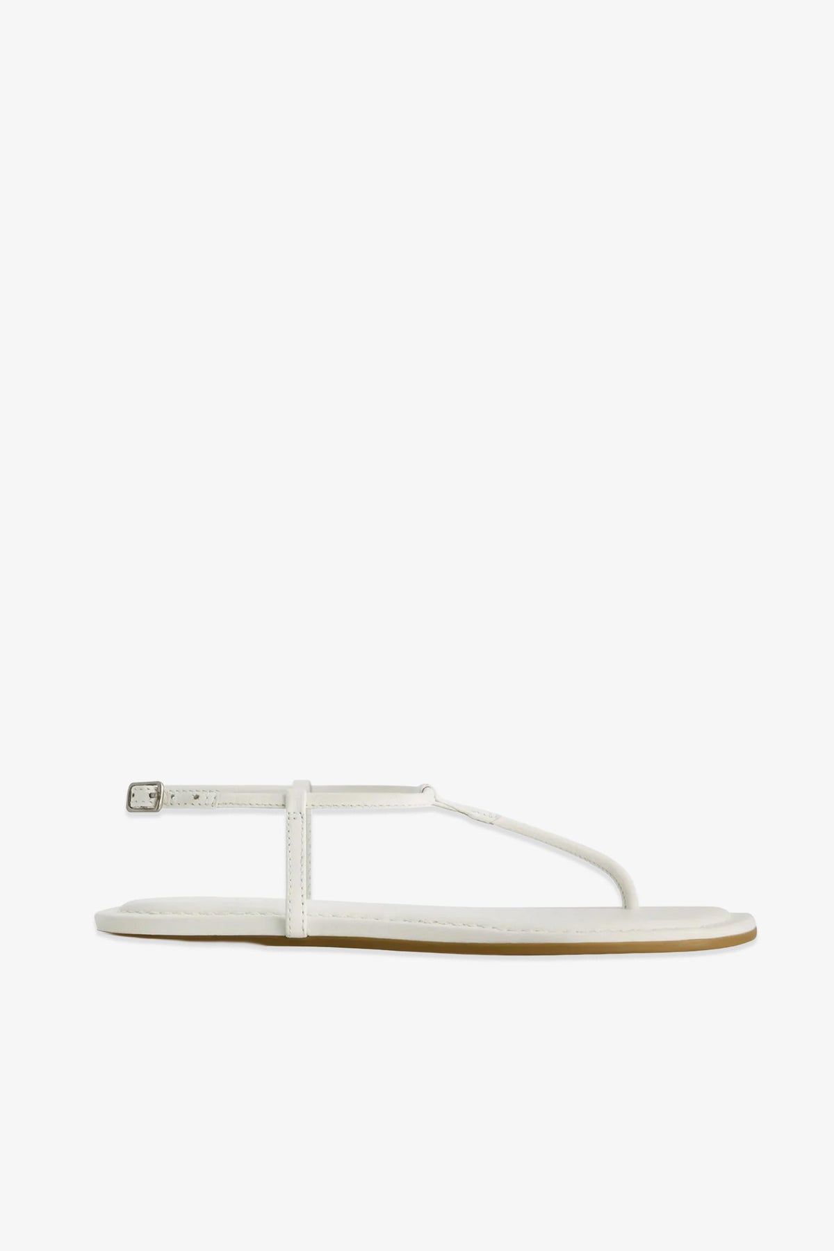 The Hercu Sandal is a minimalist white flat sandal featuring a thin strap across the toes and an ankle strap secured by a small buckle, displayed against a plain white background.