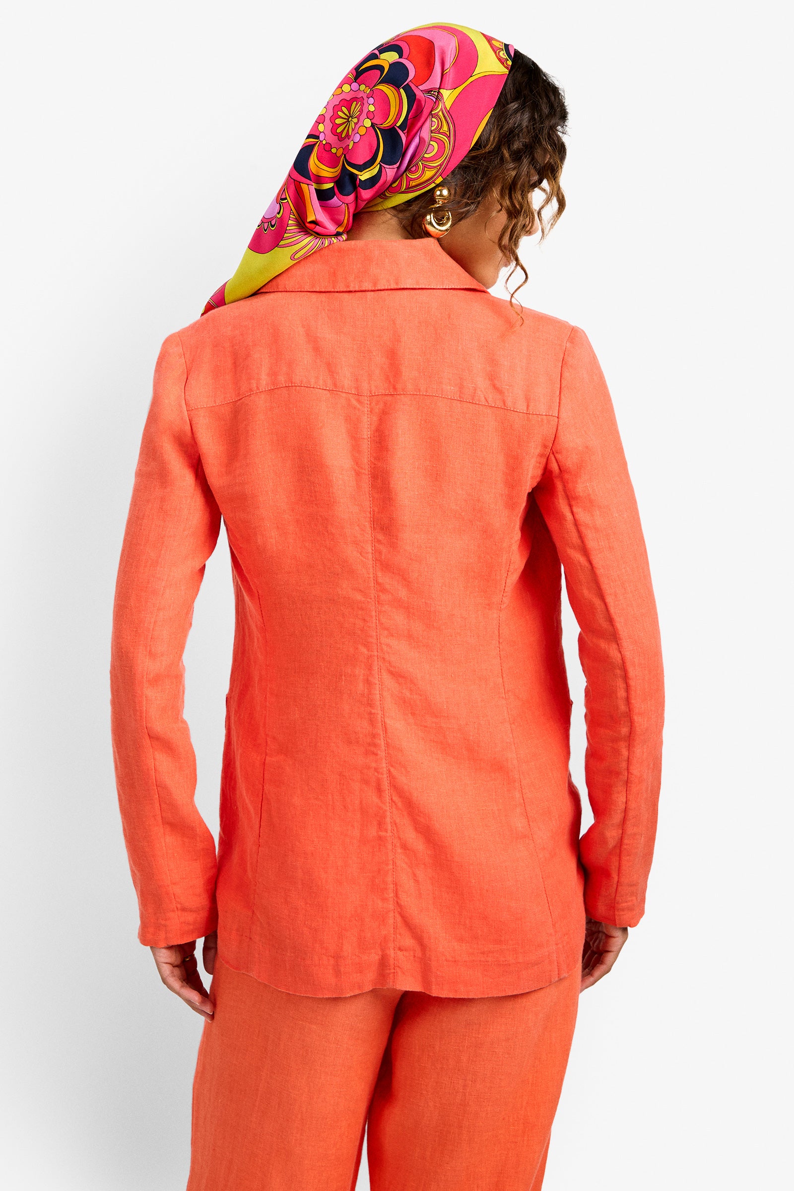 A person with curly hair is seen from behind wearing the Azurine Blazer and matching pants, paired with a vibrant headscarf featuring pink, yellow, and orange patterns.