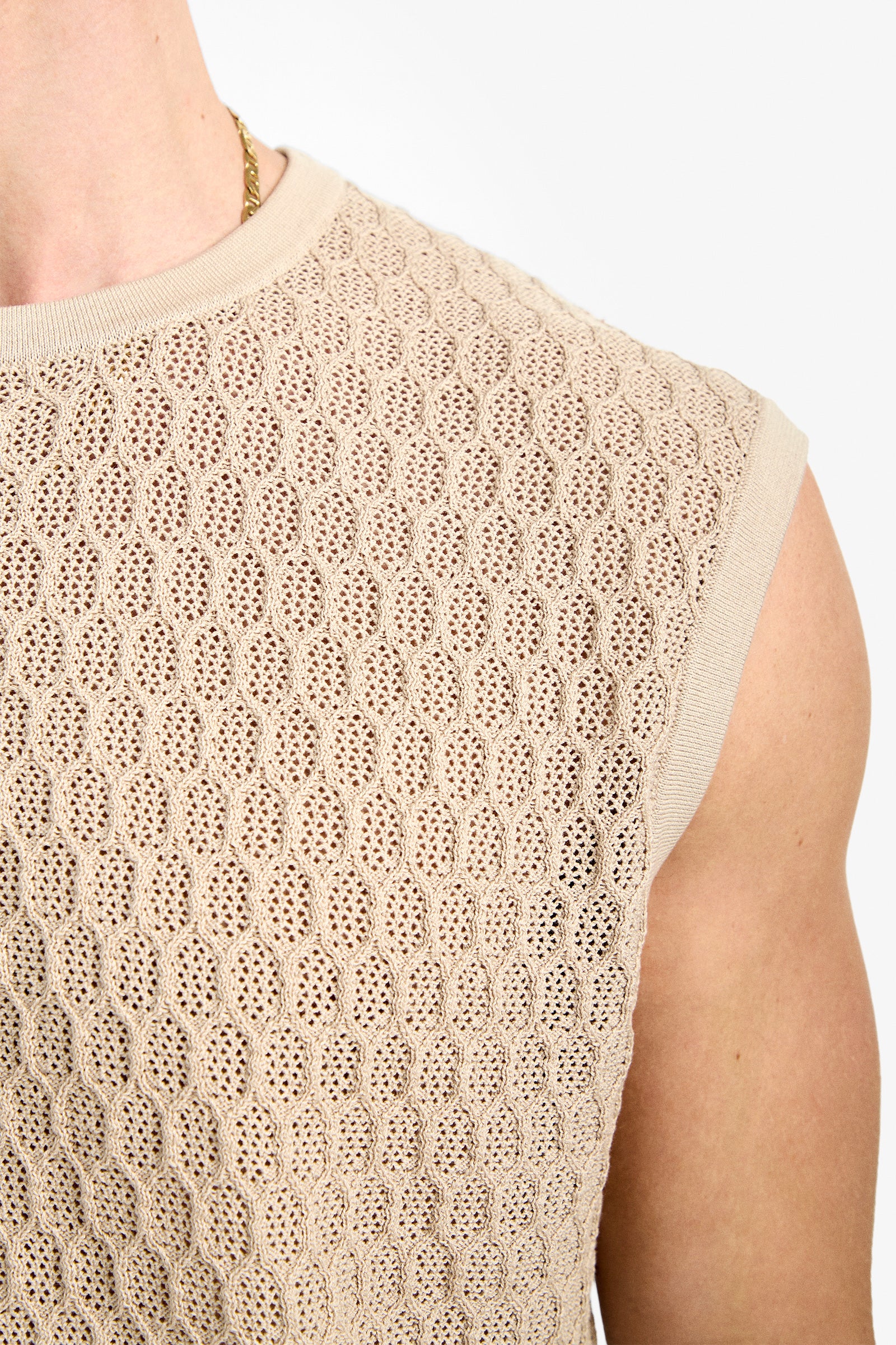 Close-up of Tovey Mesh Tan top—a sleeveless beige knit showing textured detail, part of the wearer's arm and neck, and a gold chain necklace.