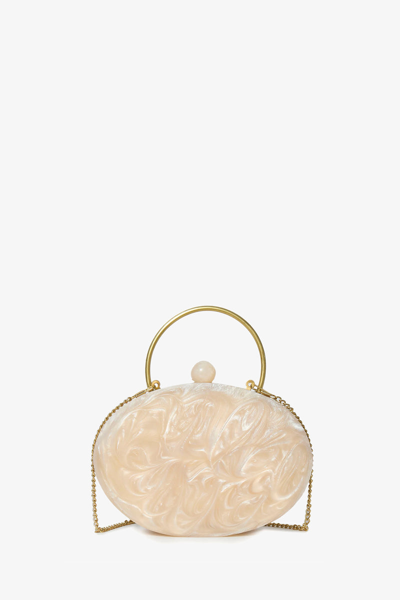 The Ivory Pearl Oval Minaudiere is an ivory, oval-shaped clutch with a marbled finish, gold metal handle, matching clasp, and gold chain strap, shown against a plain white background.
