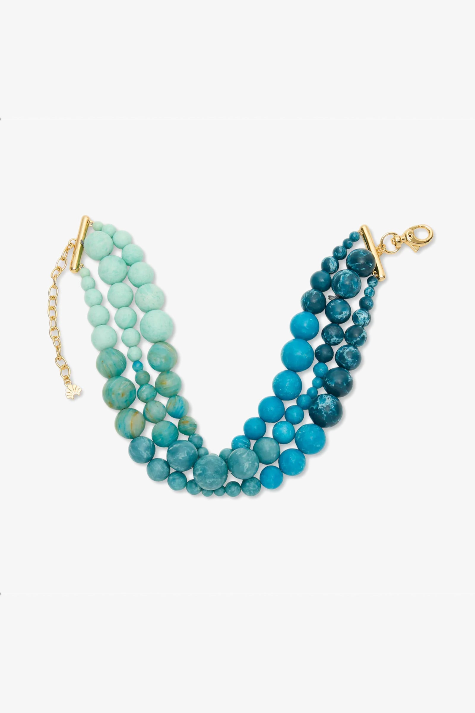 The Riviera Diana Triple Row Necklace features three strands with round beads in blue and turquoise shades, finished with gold-tone clasps and an adjustable chain, displayed on a white background.
