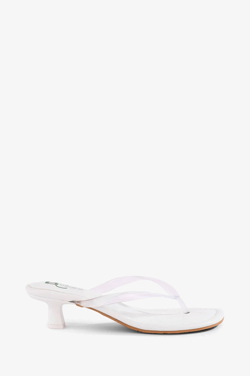 The Starbust Sandal is a white heeled sandal featuring a thong strap design and a low, cylindrical heel, shown against a plain white background.