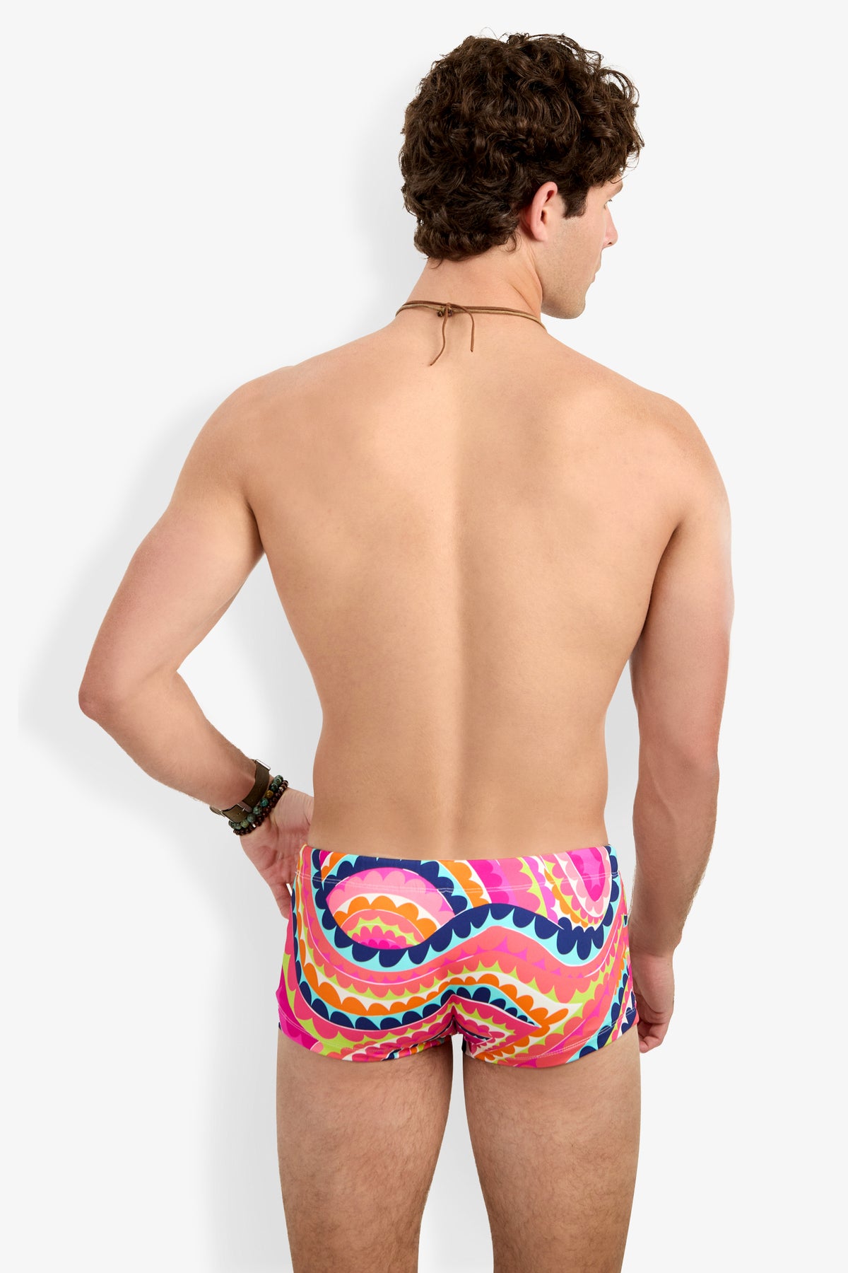 A man with short curly hair, wearing Sorrento Swim Trunk, stands with his back to the camera against a white background.