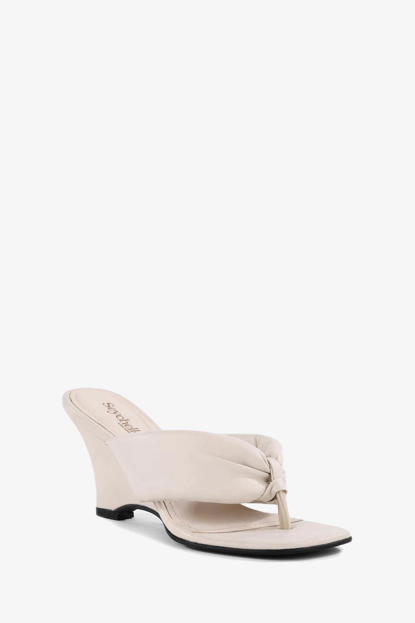 The Wishing Well Wedge is an off white sandal with a wedge heel, featuring a knotted thong strap and open toe, shown on a plain white background.