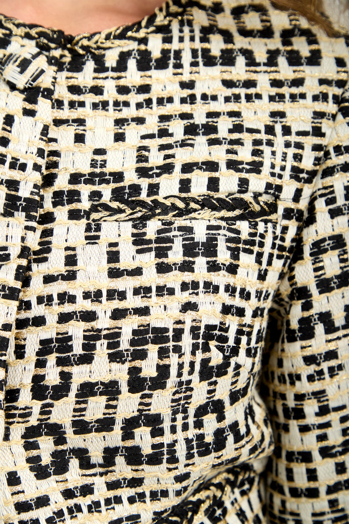 Close-up of the GIULIA JACKET, showcasing its textured fabric with a black, beige, and white geometric pattern, a chest pocket, and braided trim detail.
