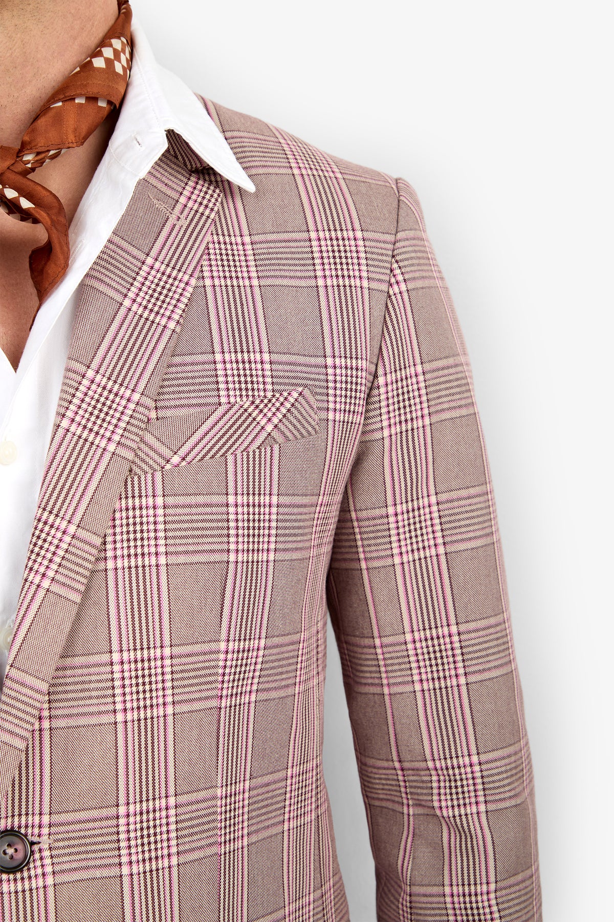 A person wearing the THURSTON BLAZER, a light plaid style over a white dress shirt with a brown patterned scarf at the neck, shown from shoulders to mid-torso against a white background.