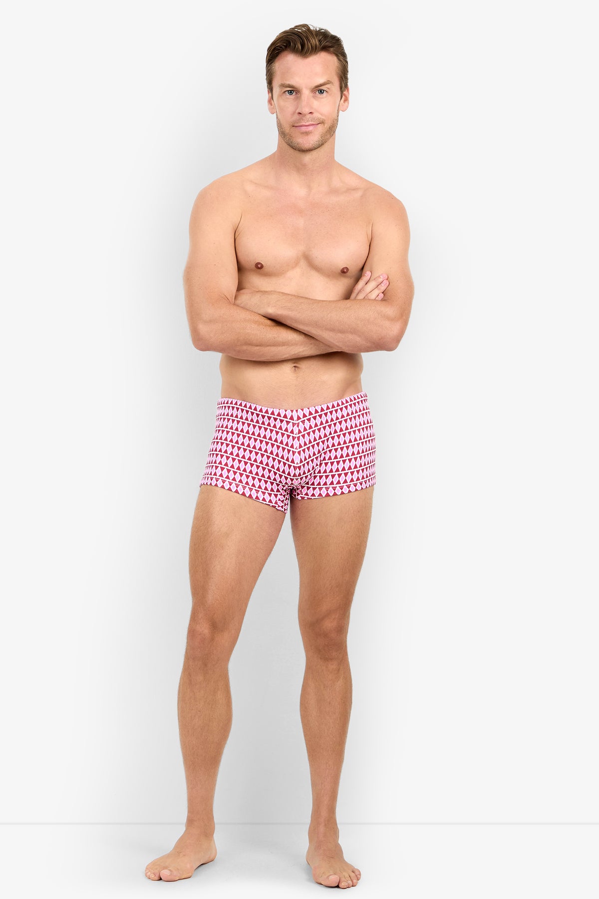 A man stands barefoot with arms crossed, wearing MONTEGO BAY SWIM TRUNK, posing against a plain white background.