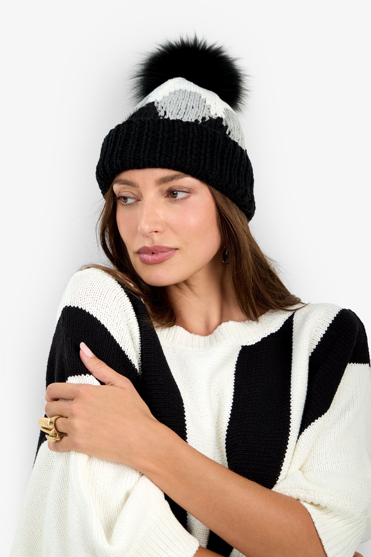 A person wearing a black and white Cavallari Hat with a black pom-pom.