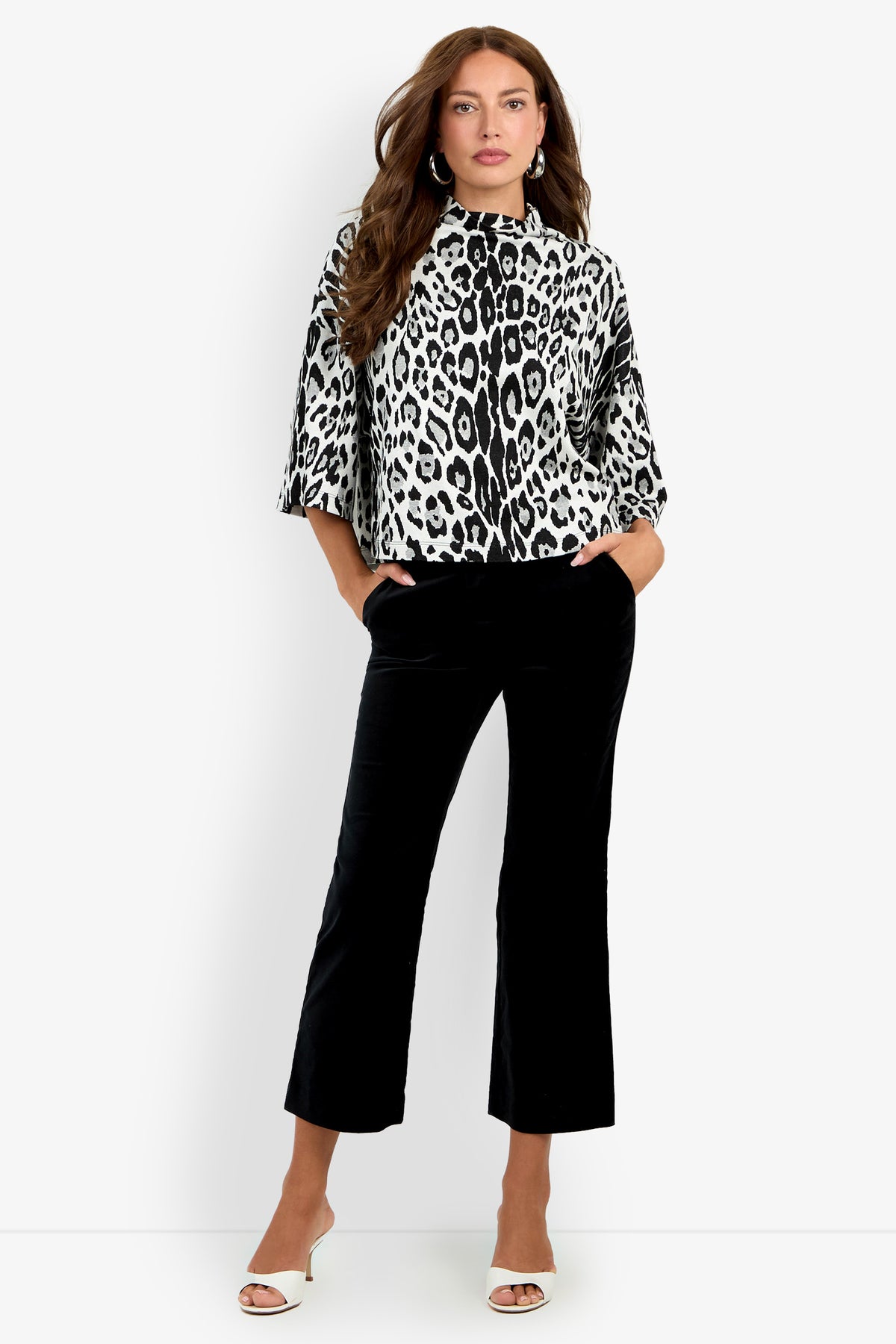 Woman wearing the Sidony Top—a black and white animal print style with three-quarter sleeves—paired with black cropped pants and white open-toe heels, standing against a white background.