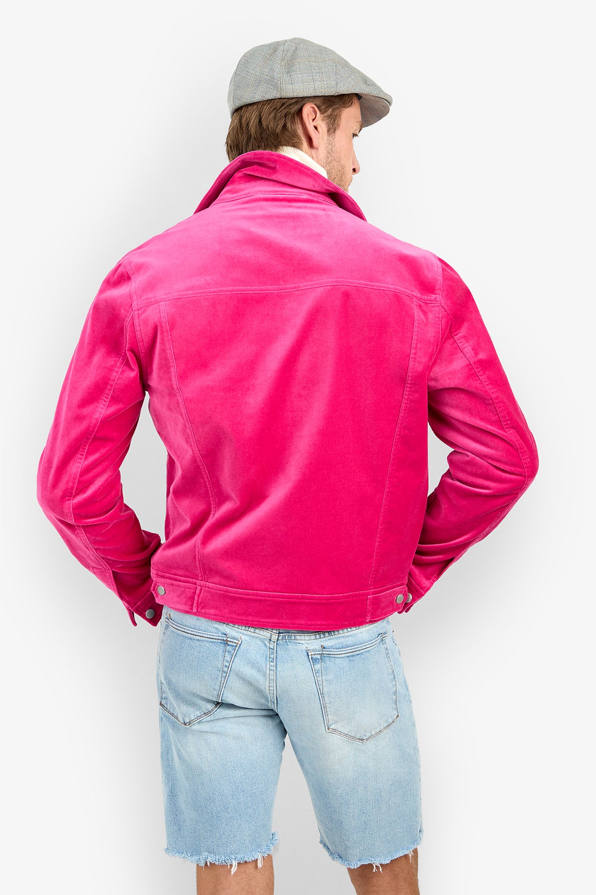 A man seen from behind wearing a bright pink Angelino Trucker Jacket and a gray flat cap.