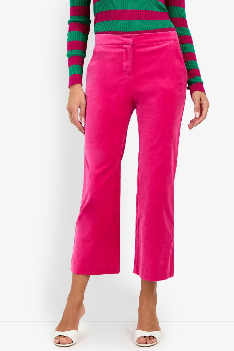 A person wearing the Westport Crop in bright pink, paired with a green and pink striped ribbed sweater and white open-toe heels, stands against a plain white background.