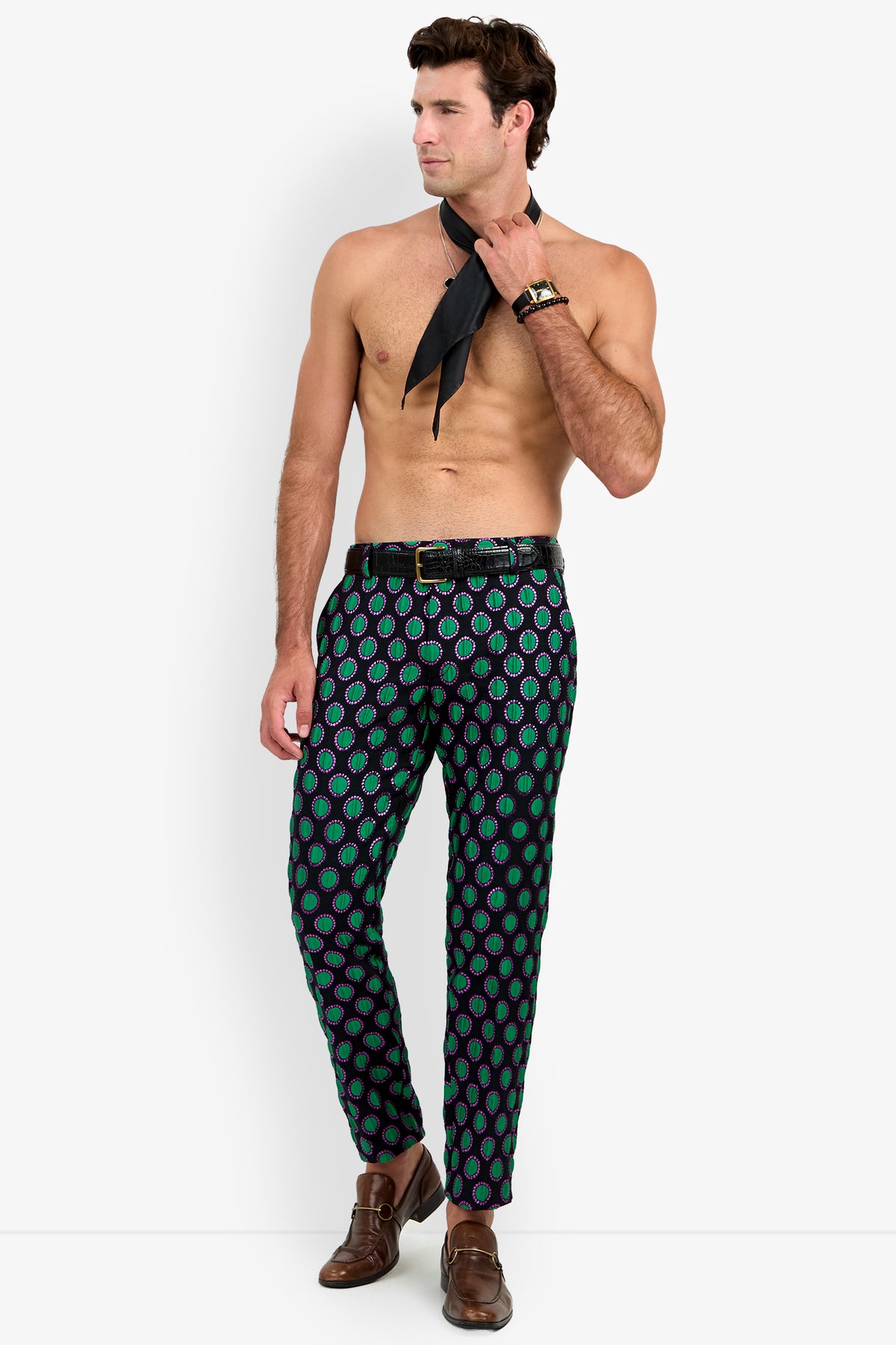 A shirtless man poses against a plain white background, wearing the Clyde Slim Trouser styled with brown shoes and holding a black necktie while looking to the side.