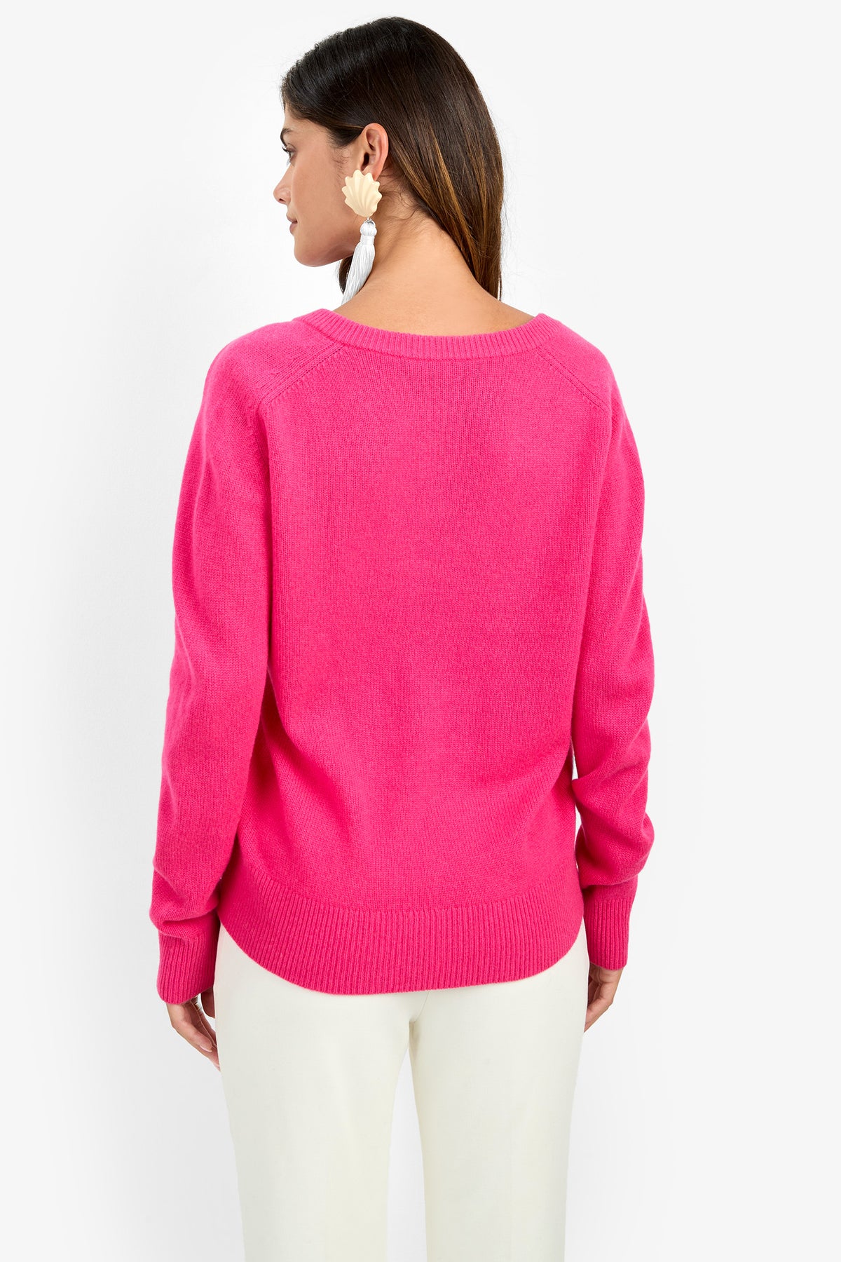 Back view of a person wearing an EVANGELINE SWEATER in bright pink, featuring a long-sleeved, crew-neck design with ribbed trim in 100% cashmere.