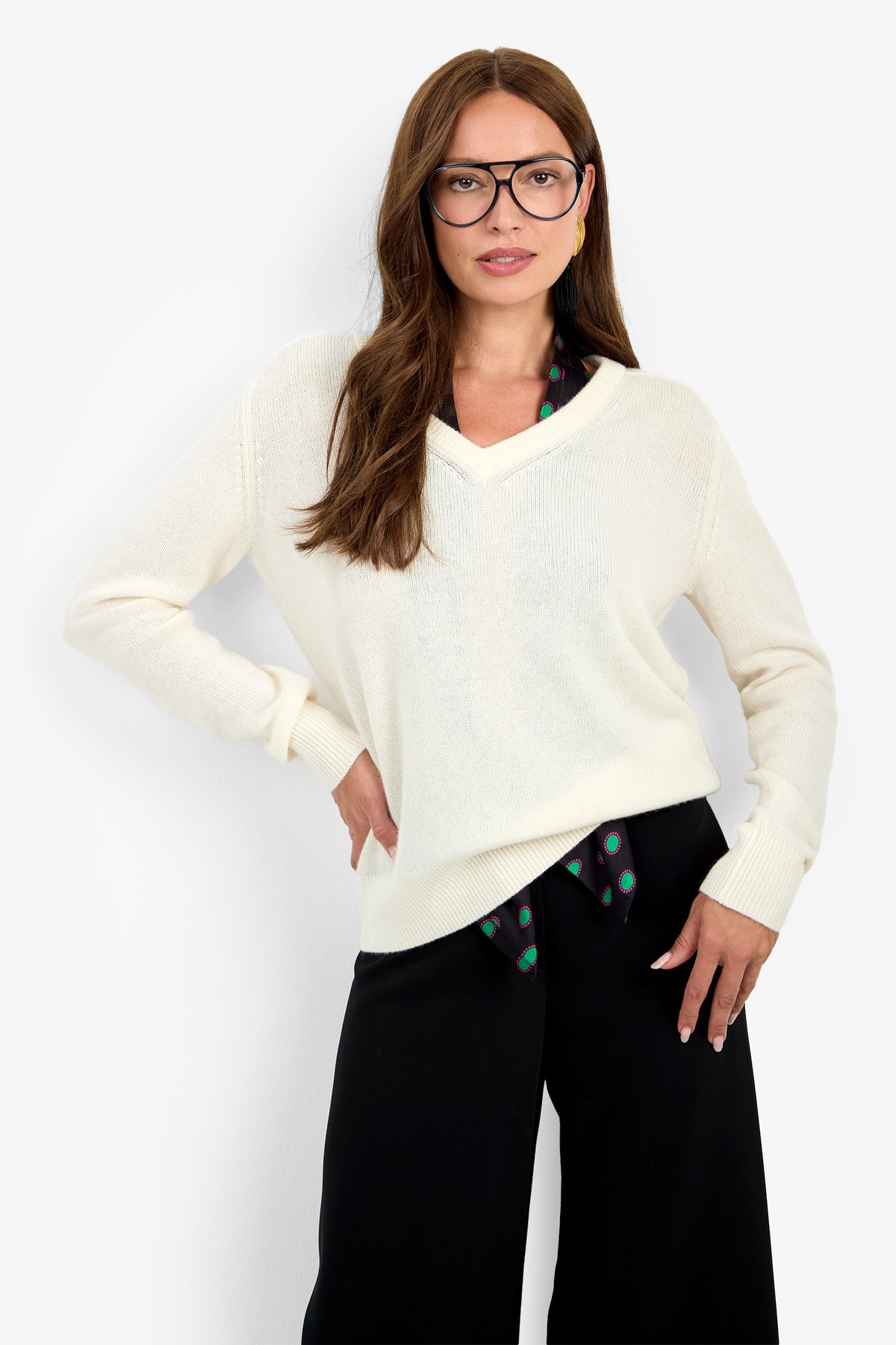 A woman wearing the cream EVANGELINE SWEATER in 100% cashmere over a patterned collared shirt and black trousers.