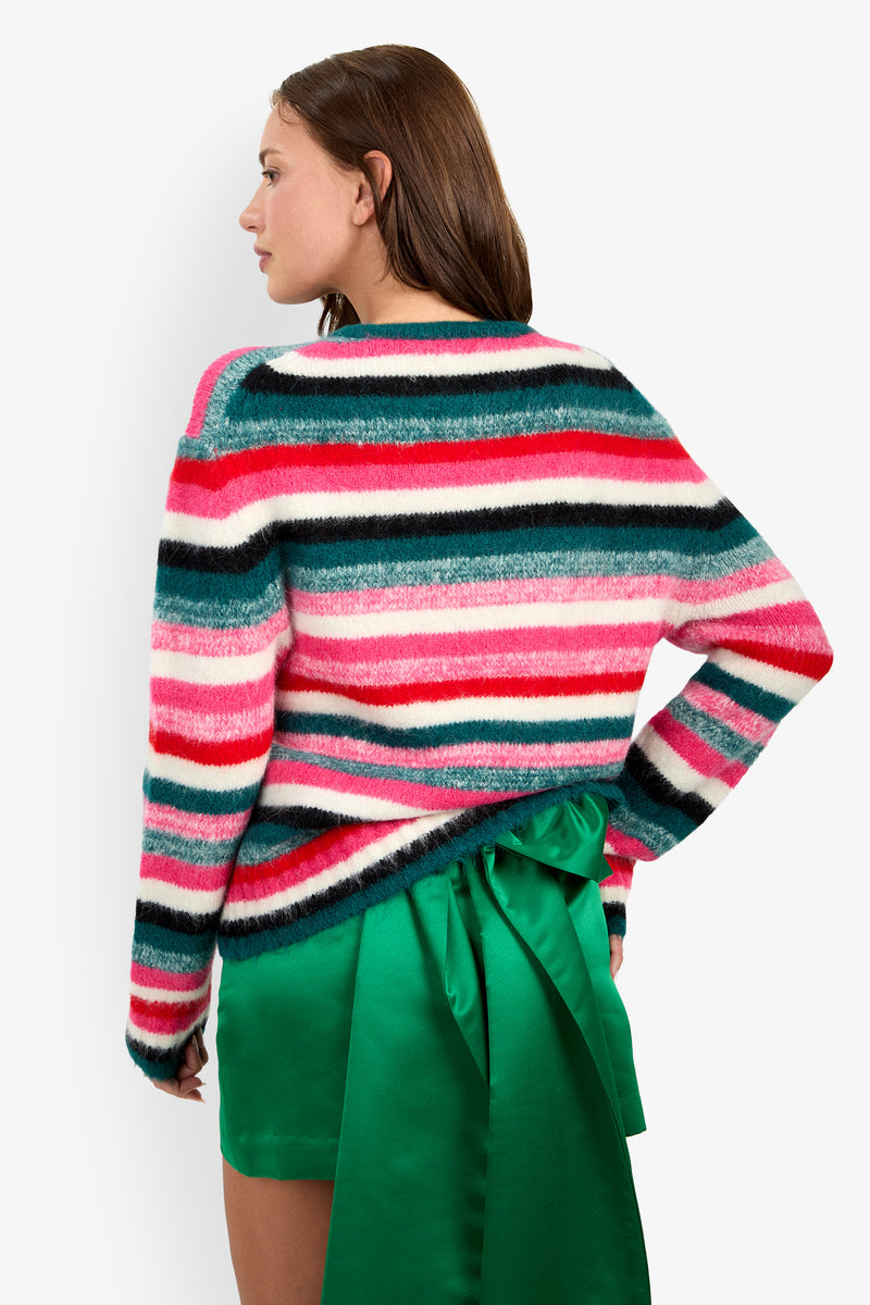 A woman wearing a multi-colored striped alpaca BARDINI PULLOVER paired with a bright green spandex skirt.