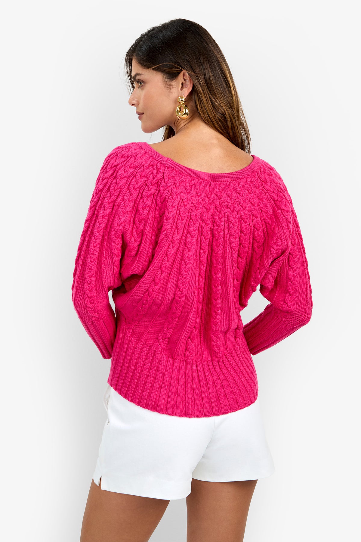 Back view of a person wearing a bright pink Tyson Knit Sweater with a wide neckline and ribbed hem.