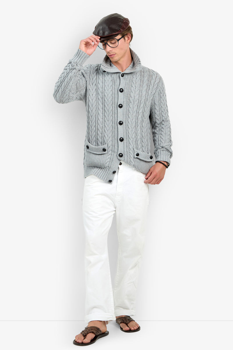 A person wearing the RALEIGH SWEATER COAT in HEATHER GREY, paired with white pants, black glasses, and a black cap, stands while touching the brim of the cap with one hand and looking down.
