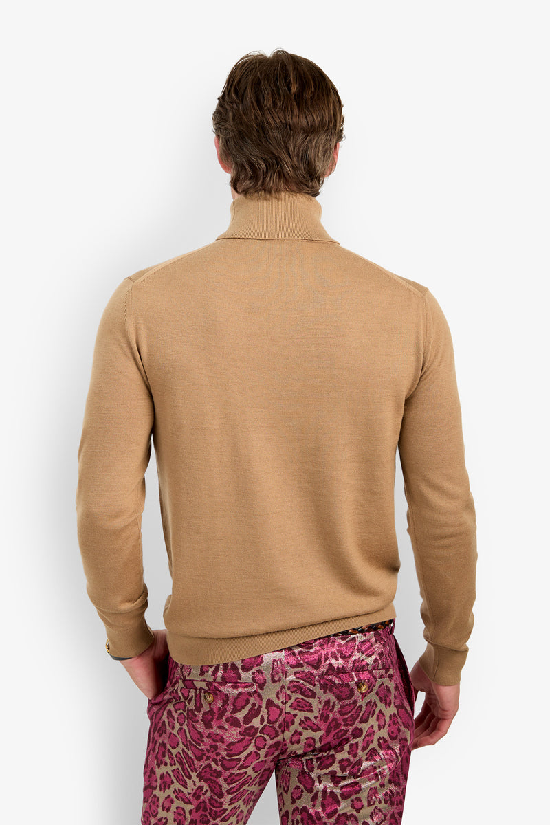 A person stands facing away, wearing the WOODROW TURTLENECK in tan and vibrant pink leopard-print pants against a white background.