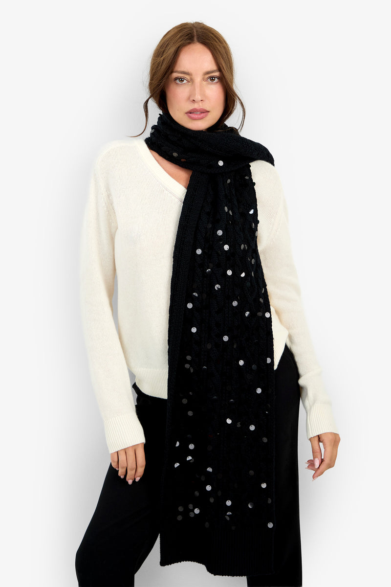A person wears a DALIDA SEQ. SCARF, a long black wool scarf decorated with scattered silver sequins.