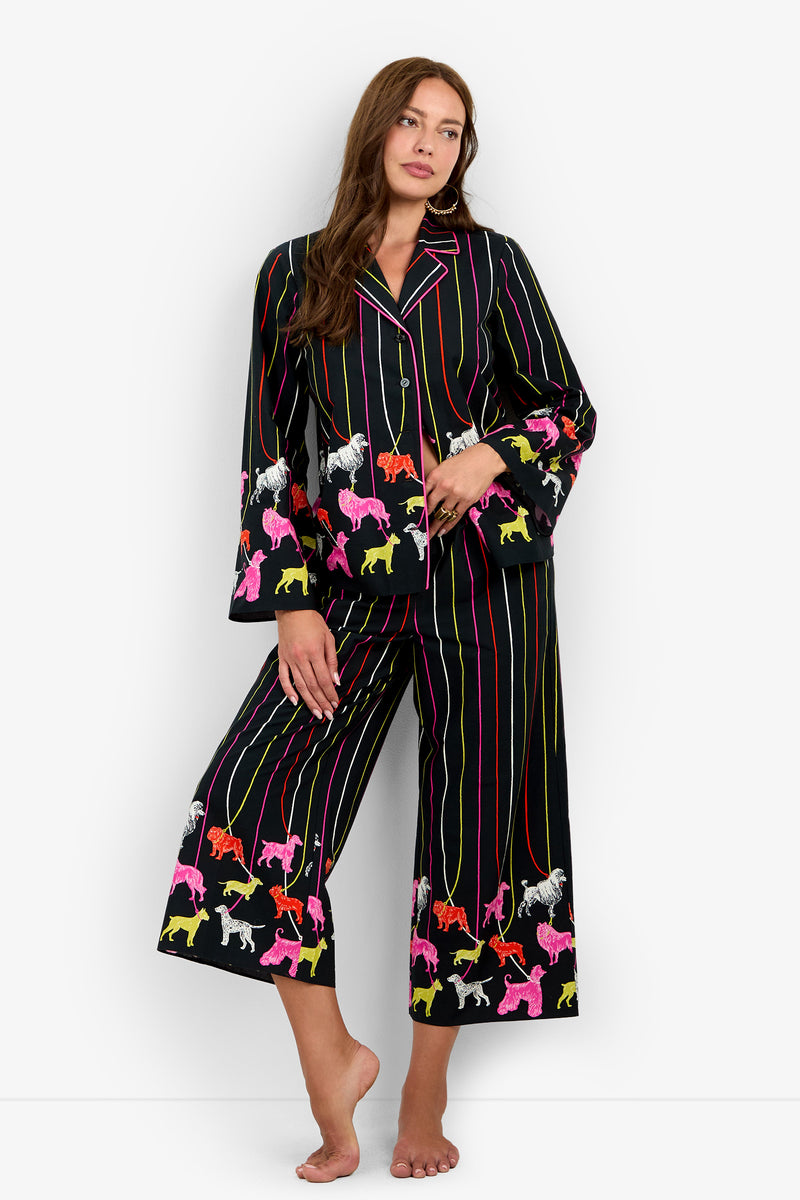 A person wearing a RUBEE PANT set in black with colorful vertical stripes and a pattern of various dog breeds on leashes.