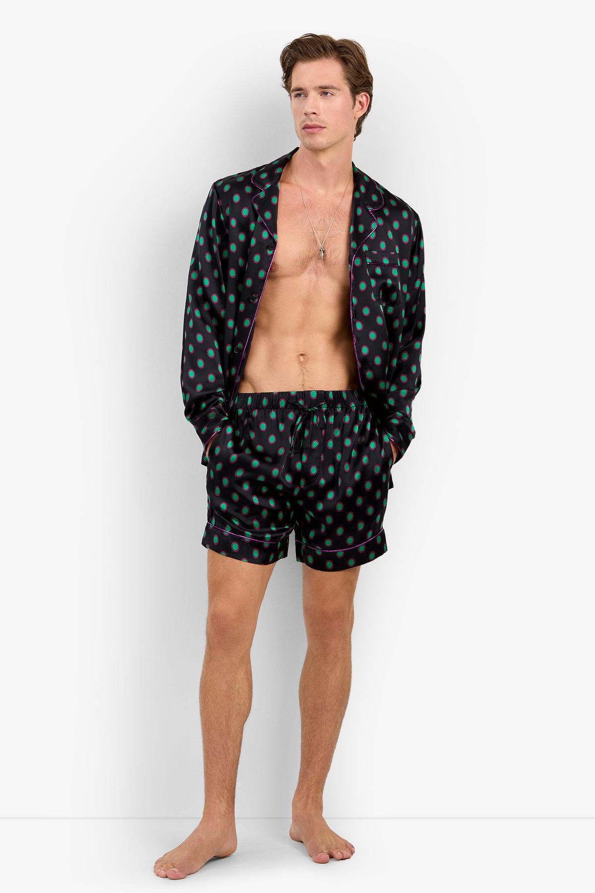 A man wearing a Silk Long Sleeve PJ Top and matching shorts with a green polka-dot pattern and magenta piping.