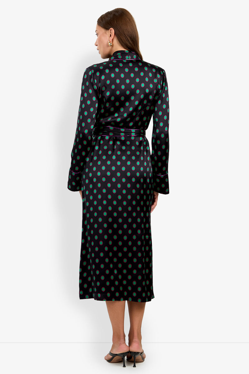 A person wearing the ADALYNN ROBE, a mid-length robe in black 100% silk with a green and magenta polka dot pattern, tied at the waist with a belt.