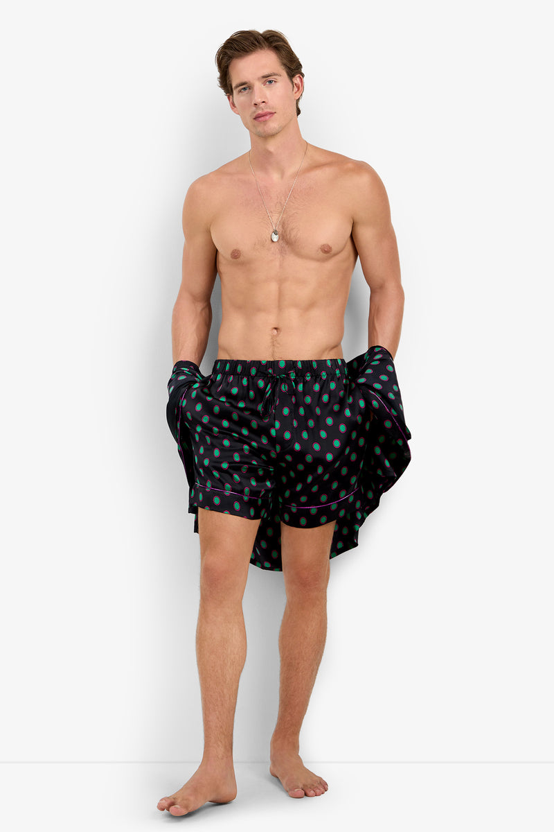 A man wearing PJ SHORT in pure silk with a teal polka dot pattern and purple piping.