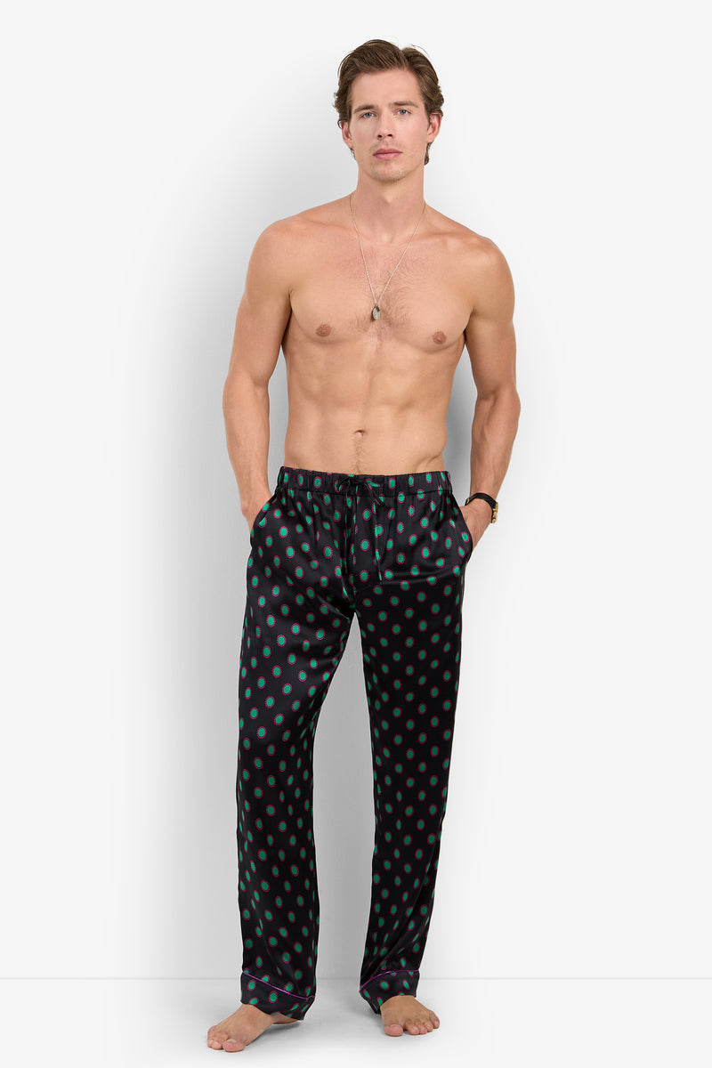 A shirtless man wearing Silk PJ Pant black pajama pants with a green and red polka dot pattern and a drawstring waist.