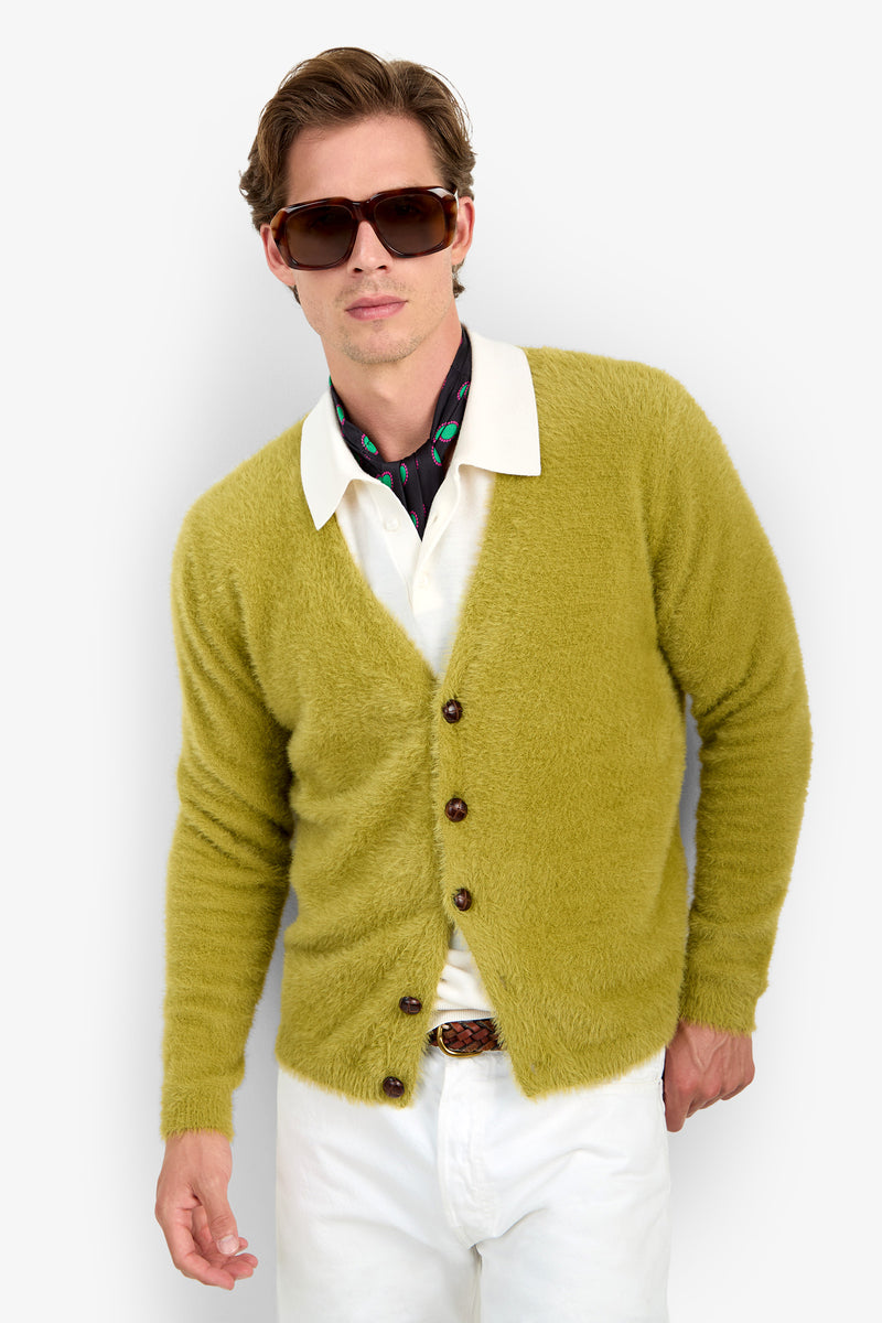 A man wearing a SCOTT FUZZY CARDIGAN in fuzzy chartreuse polyester over a white collared shirt, a dark patterned neck scarf, and brown sunglasses.