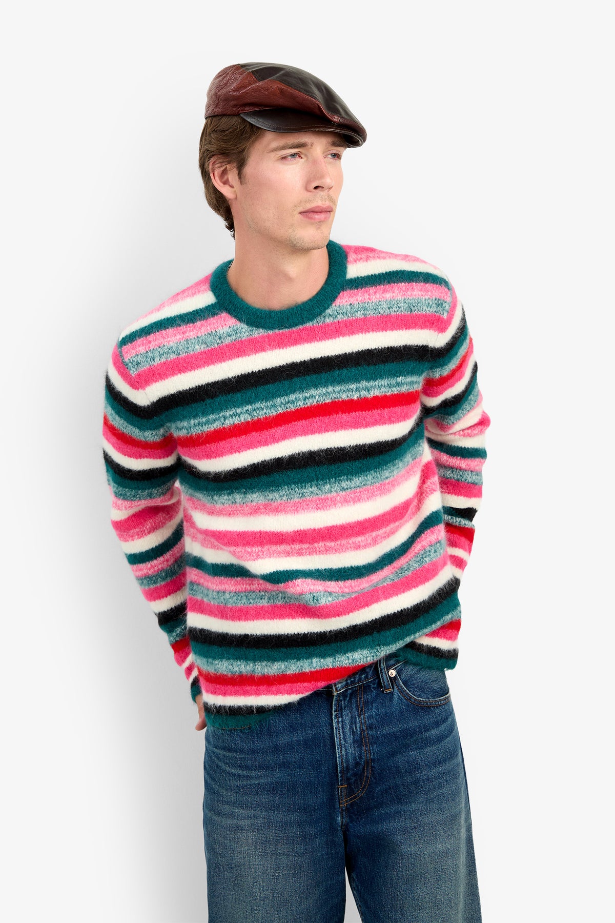A man wearing the MR. BARDINI fuzzy, multi-colored striped cashmere sweater, blue jeans, and a leather flat cap.