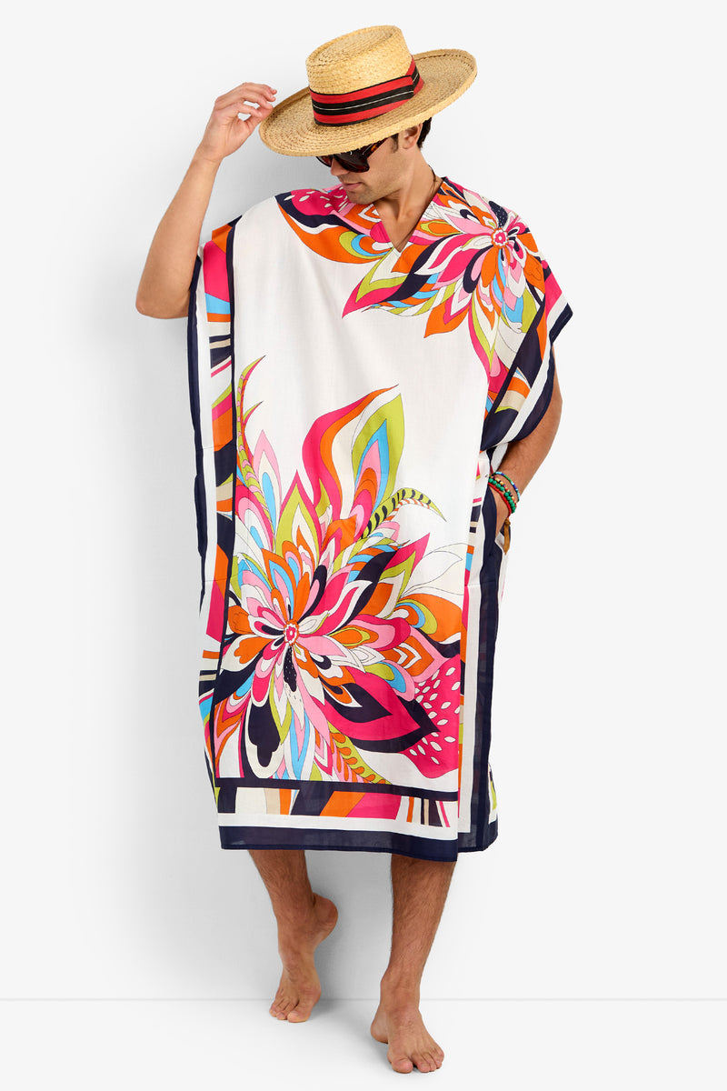 A person wearing the ST. MARTIN colorful floral-patterned 100% cotton kaftan, a straw hat with a red band, and sunglasses stands barefoot against a plain white background.