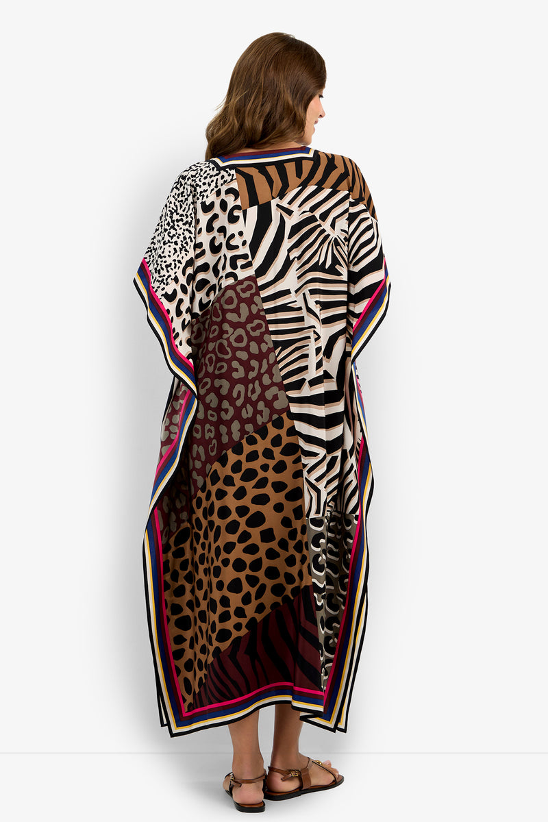 A woman faces away, wearing the Vintage Animal Caftan Dress featuring a loose, flowing fit with bold leopard, zebra, and cheetah prints in brown, black, and white tones, finished with a striped border.