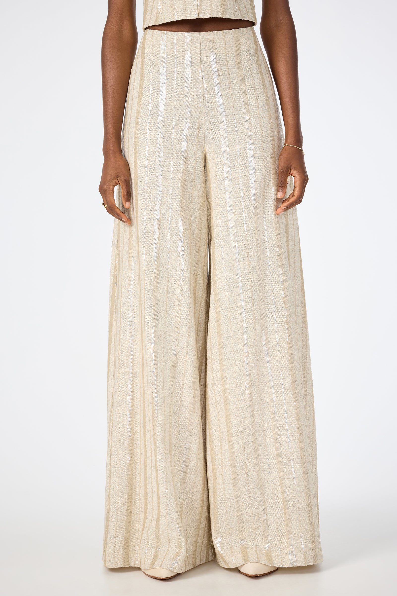 Someone wearing Nice Wide-Leg Pants in Biarritz Beige with a subtle shiny stripe pattern, standing against a plain white background.