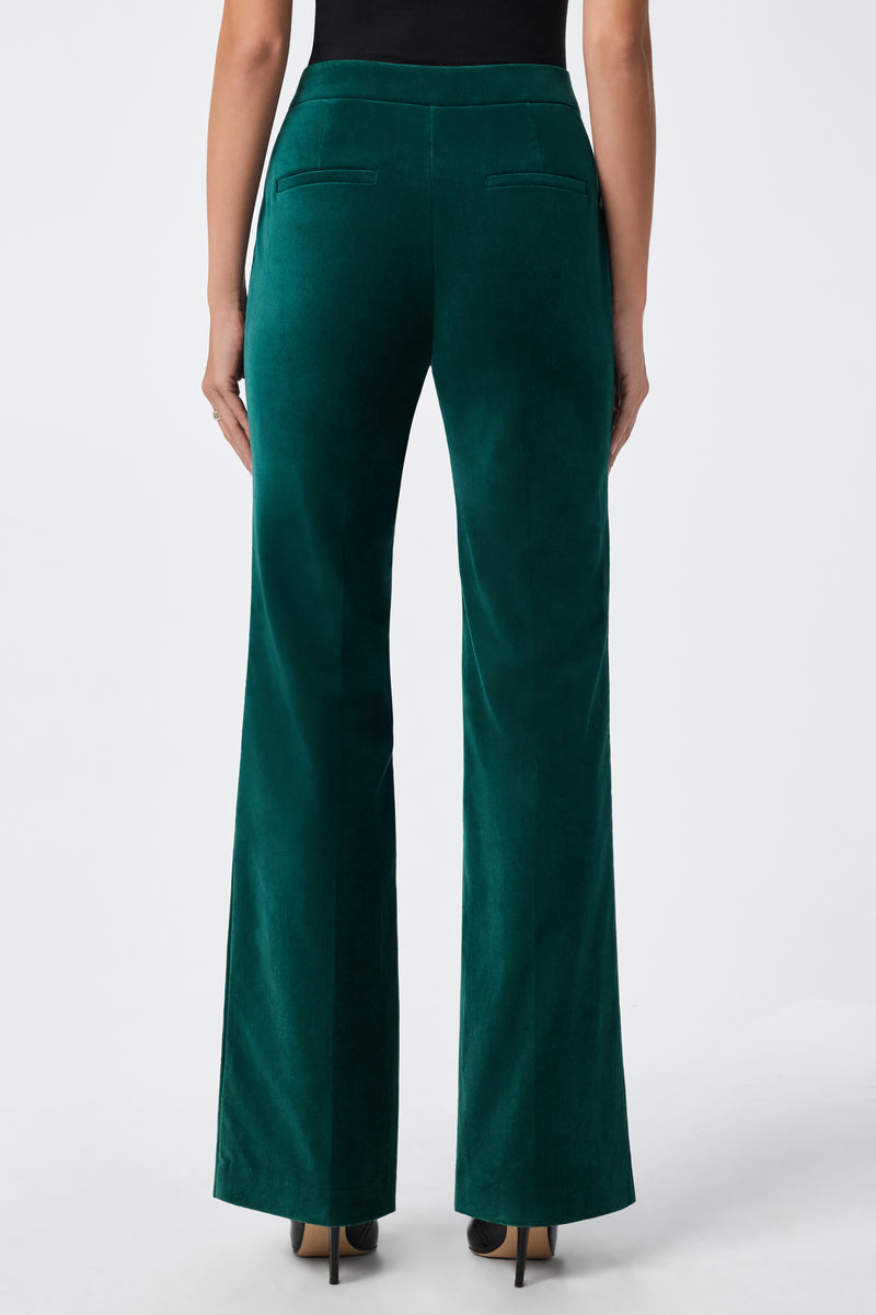 A person wearing the Westport Pant—high-waisted, dark green velvet—paired with black heels, shown from the back against a plain white background.
