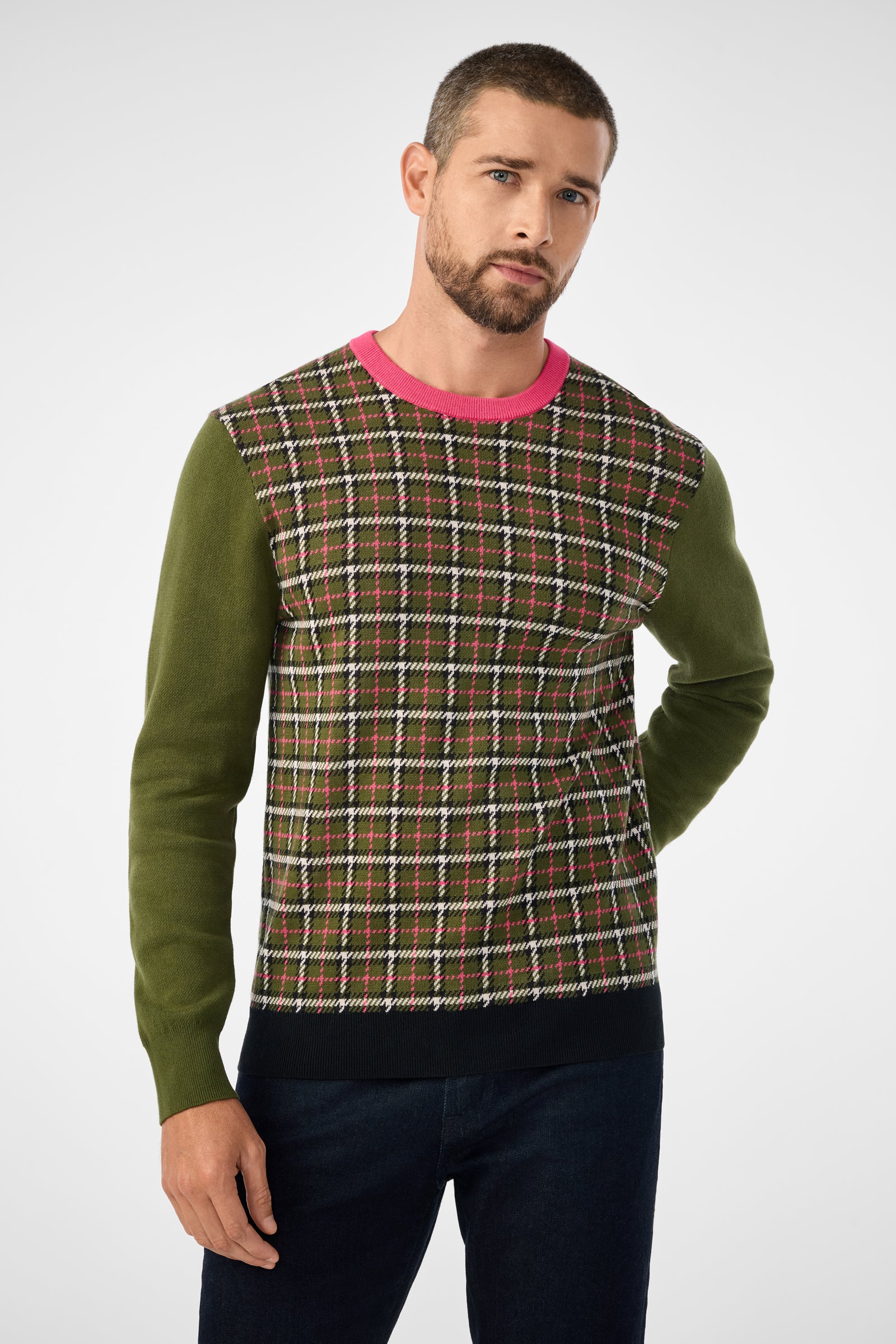 A man with short hair and a beard wears the Buchanan Long-Sleeve Crewneck in Multi, standing against a plain light background with one hand behind his back.
