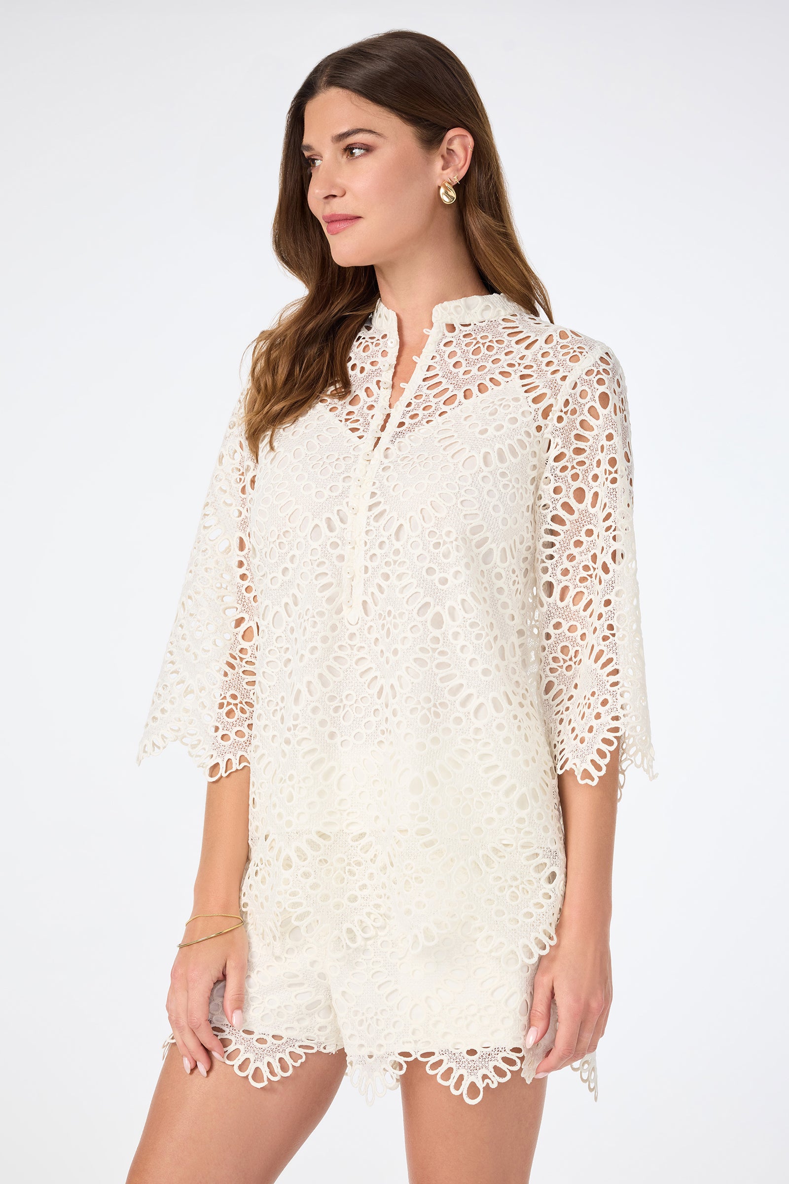 A woman wearing the Martigues Lace Top with gold hoop earrings and a gold bracelet stands against a plain white background.