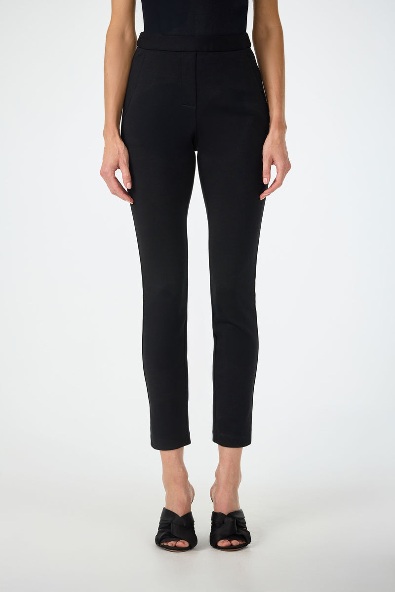 A person models the Honey Straight Leg Pants in black with black heeled sandals, standing against a plain white background. Only the lower torso and legs are visible.