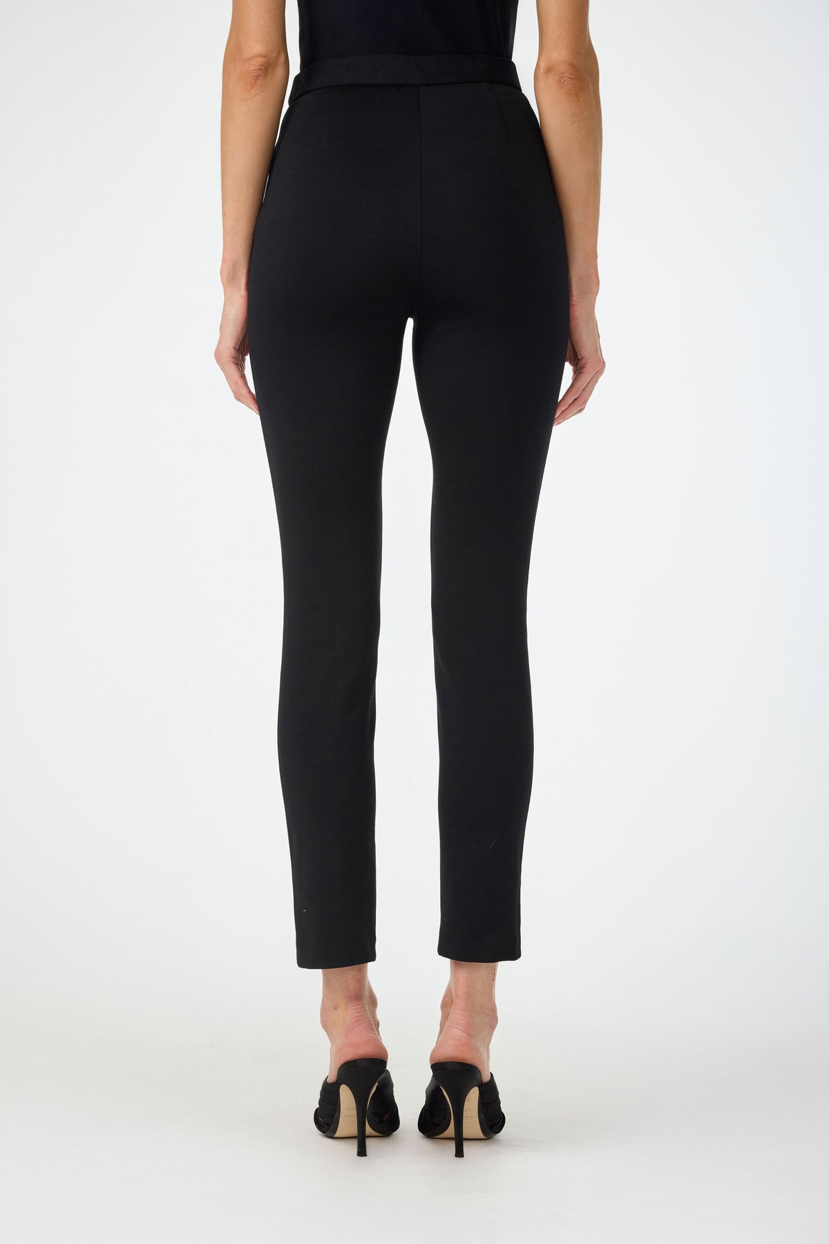 A person stands against a plain white background, shown from the back wearing Honey Straight Leg Pants and black high-heeled shoes. The full length of the pants and lower arms are visible.