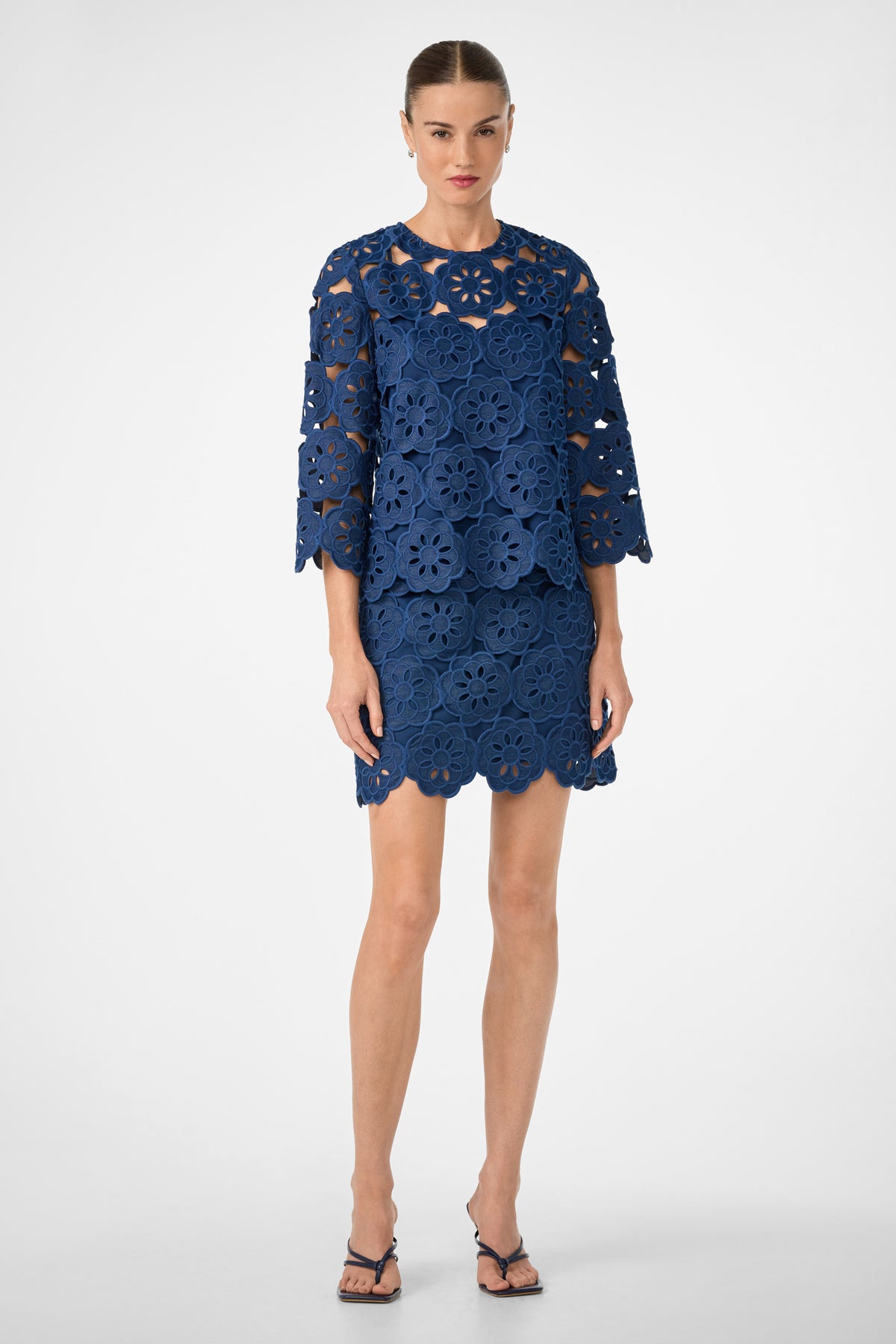 A woman poses in a studio wearing the Kabosu Top – Kusho Embroidery, styled with black strappy heels and slicked-back hair.