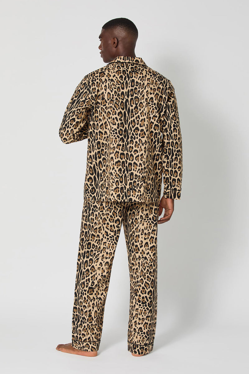 A man stands barefoot facing away, wearing the Leopard Stripe Mens Classic Pj set with a bold leopard print pattern, against a plain white background.