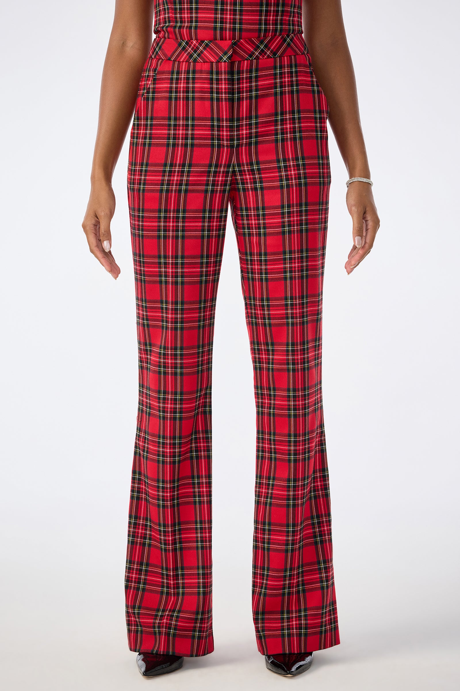 A person wearing Gorecki Pant, high-waisted with red and green plaid flared legs, shown from the waist down against a plain white background.