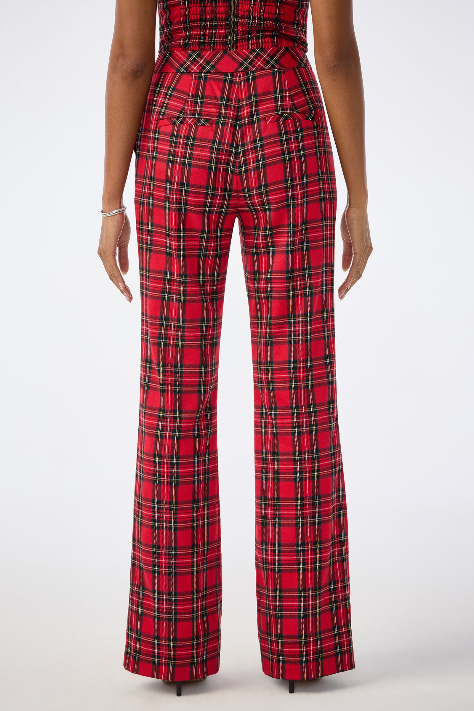 A person stands with their back to the camera, wearing the Gorecki Pant—high-waisted, red plaid with a slight flare—arms relaxed at their sides against a plain white background.