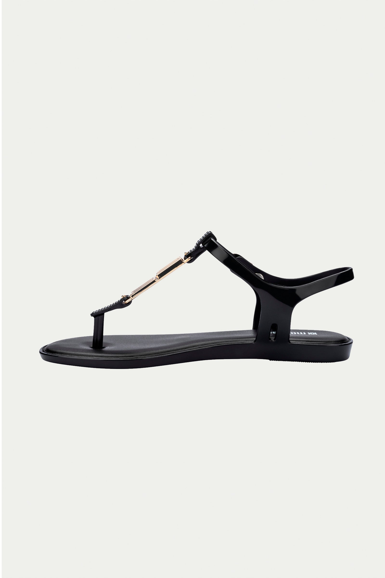 The Melissa Solar Chic T-Strap Sandal in black features a thong toe, gold-tone chain detail on the upper strap, and an adjustable heel strap, shown on a plain white background.