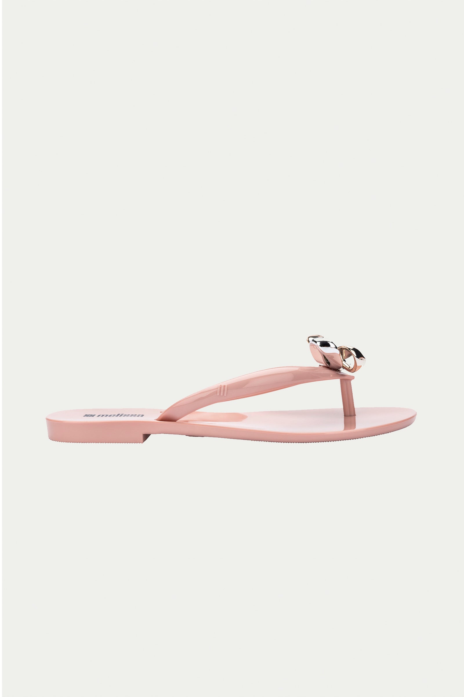 The Melissa Harmonic Eclipse Bow Sandal in pink features a light pink thong strap design with a metallic bow, shown in profile on a plain white background.